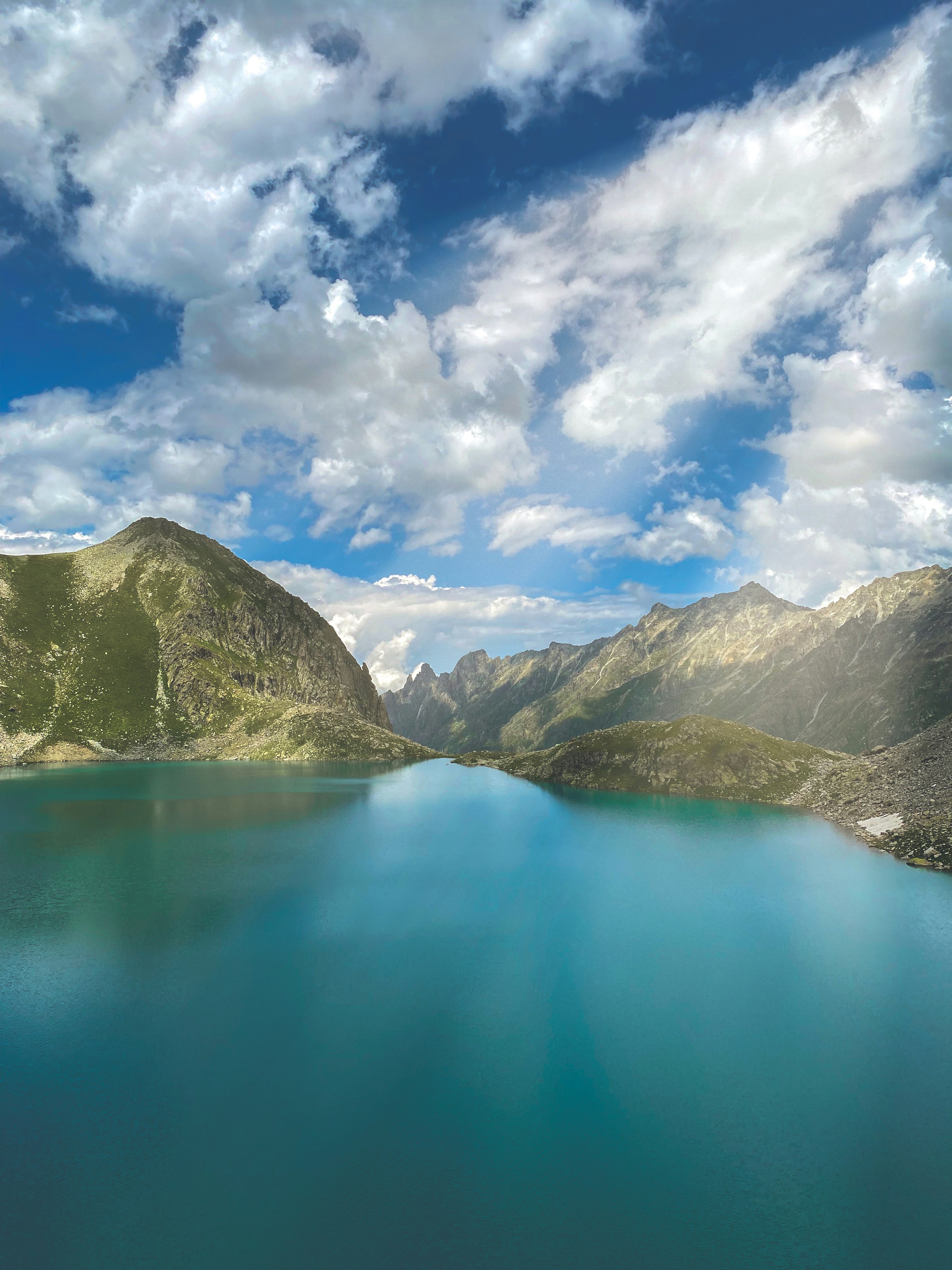 green and brown mountains beside blue sea under blue sky during daytime